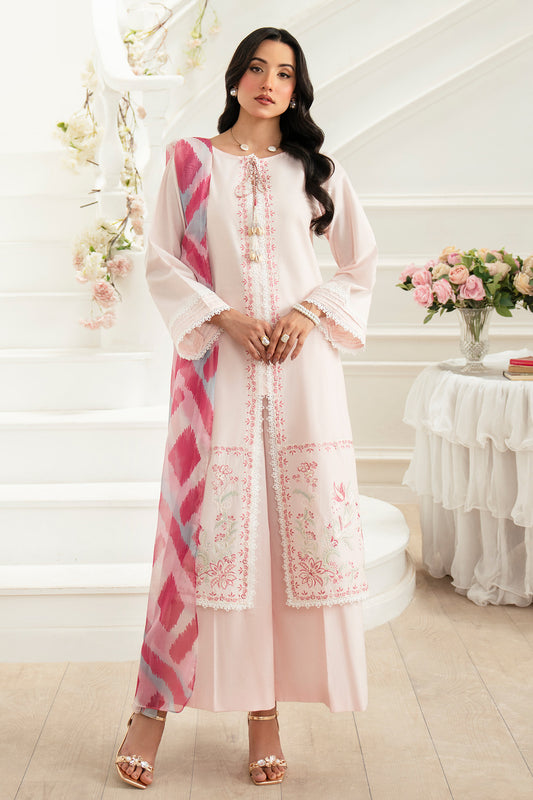 Woman in a white and pink embroidered traditional outfit in a decorated room.