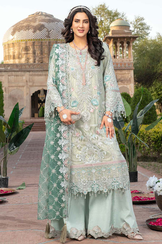 Woman in a light green embroidered outfit standing in front of architectural structures.