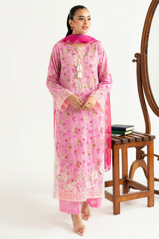 Woman wearing a pink traditional outfit with floral patterns, standing next to a wooden stool and mirror.