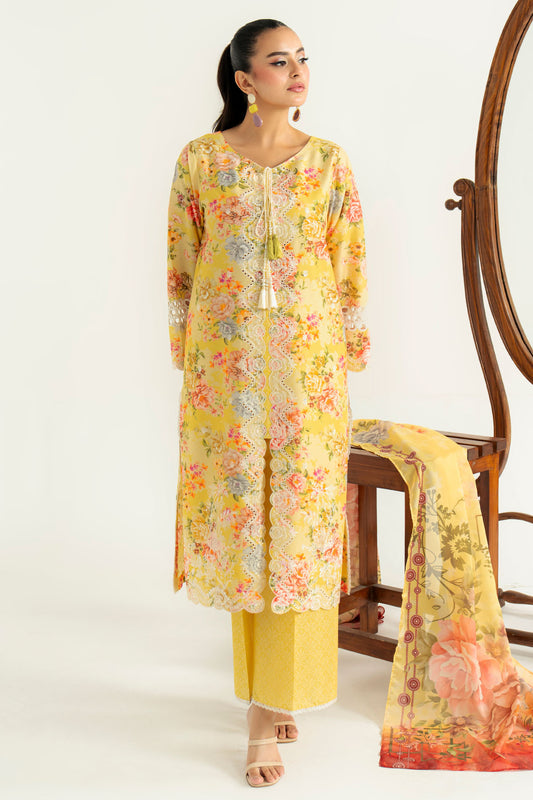 Woman wearing a yellow floral outfit with a matching scarf, standing next to a wooden chair.