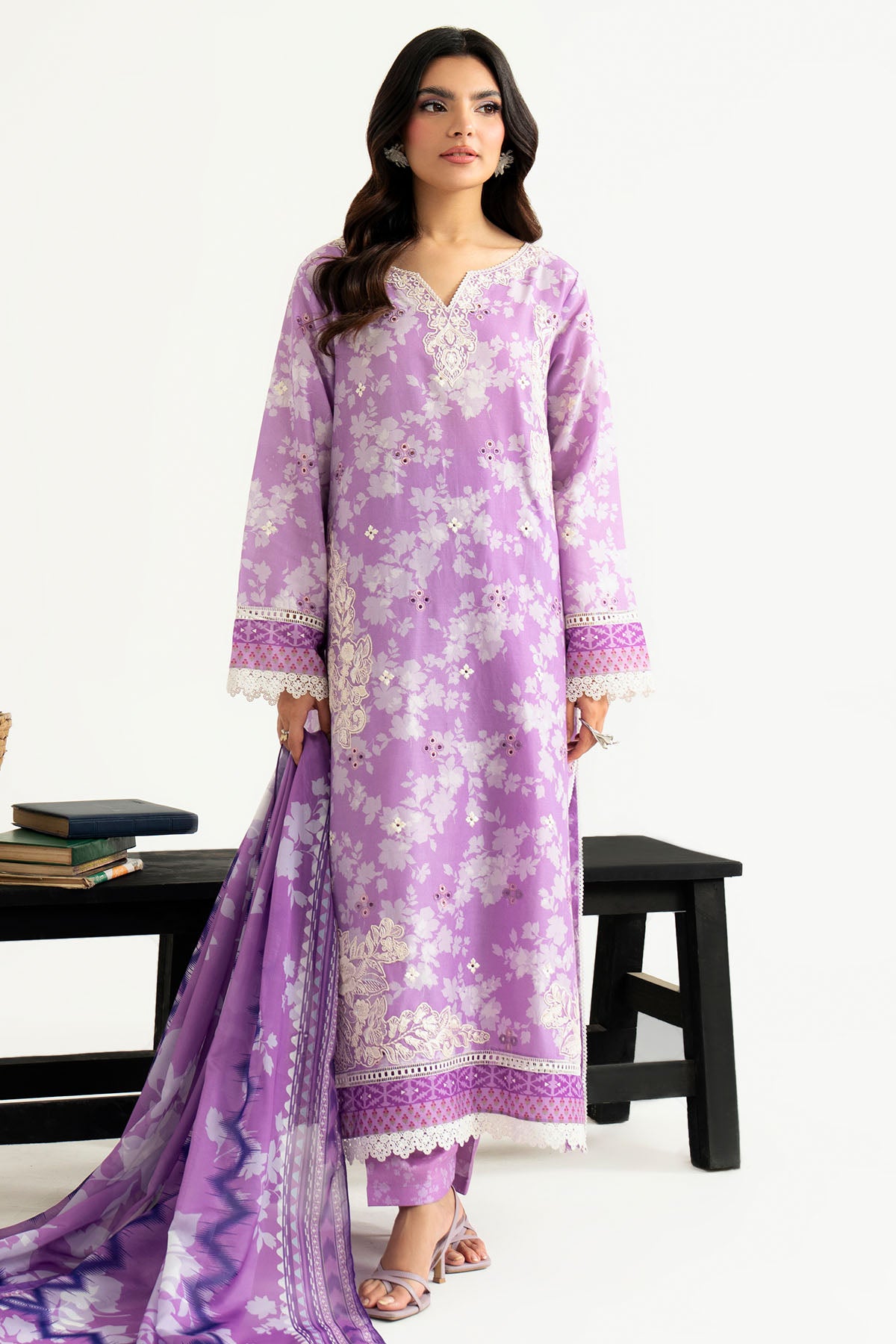 Woman wearing a purple floral dress with a matching dupatta on a white background