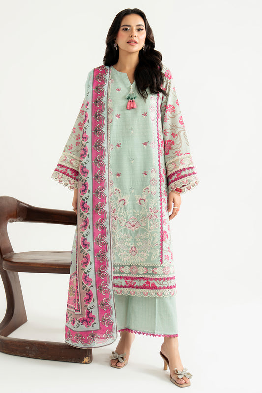 Woman wearing a light green and pink embroidered traditional outfit on a white background