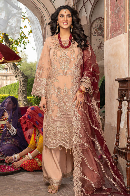 Woman in traditional attire standing in a decorative outdoor setting with other people.