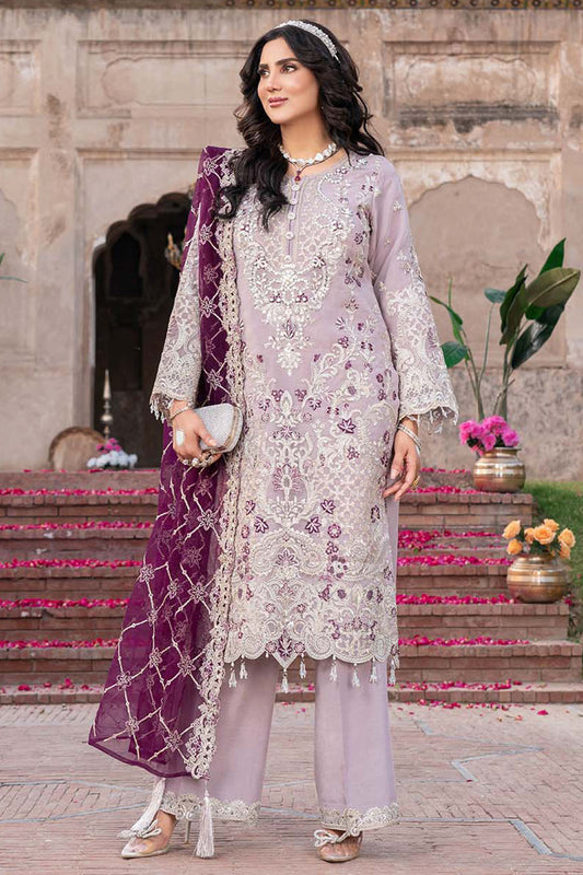 Woman in a light purple embroidered outfit with a purple dupatta standing in front of a stone building.