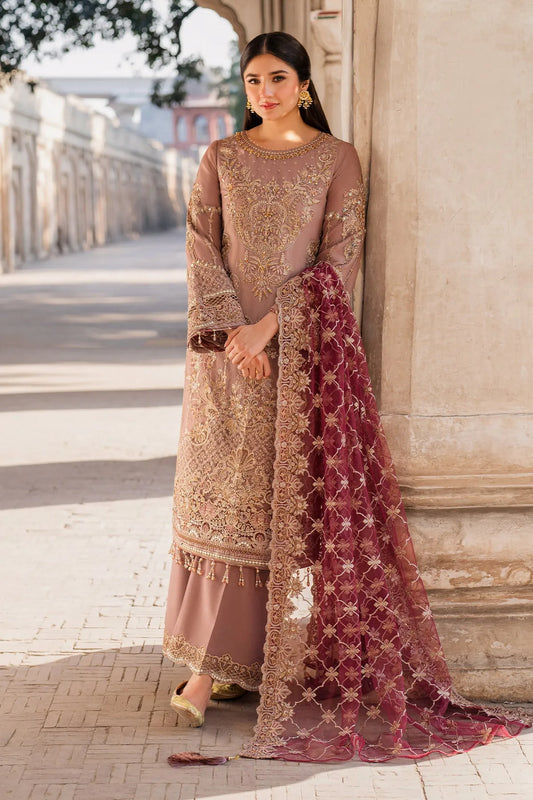 A woman wearing a pink and gold embroidered shirt with a contrasting red dupatta and a dyed raw silk trouser. The ensemble features intricate embroidery and an organza dupatta.