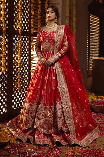 A woman wearing a traditional red and gold bridal lehenga with detailed embroidery and organza borders.