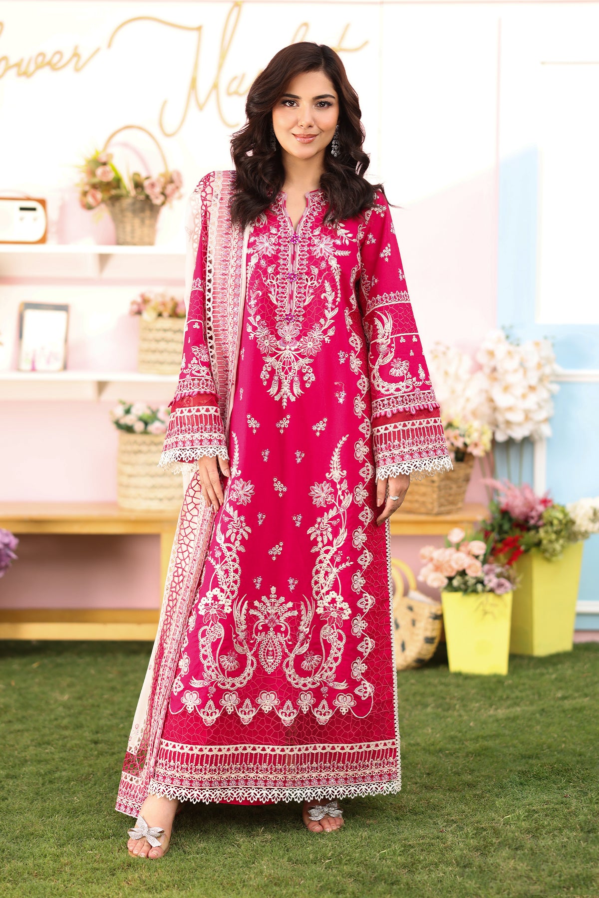 A woman wearing a hot pink lawn suit with embroidered details and a chiffon dupatta.