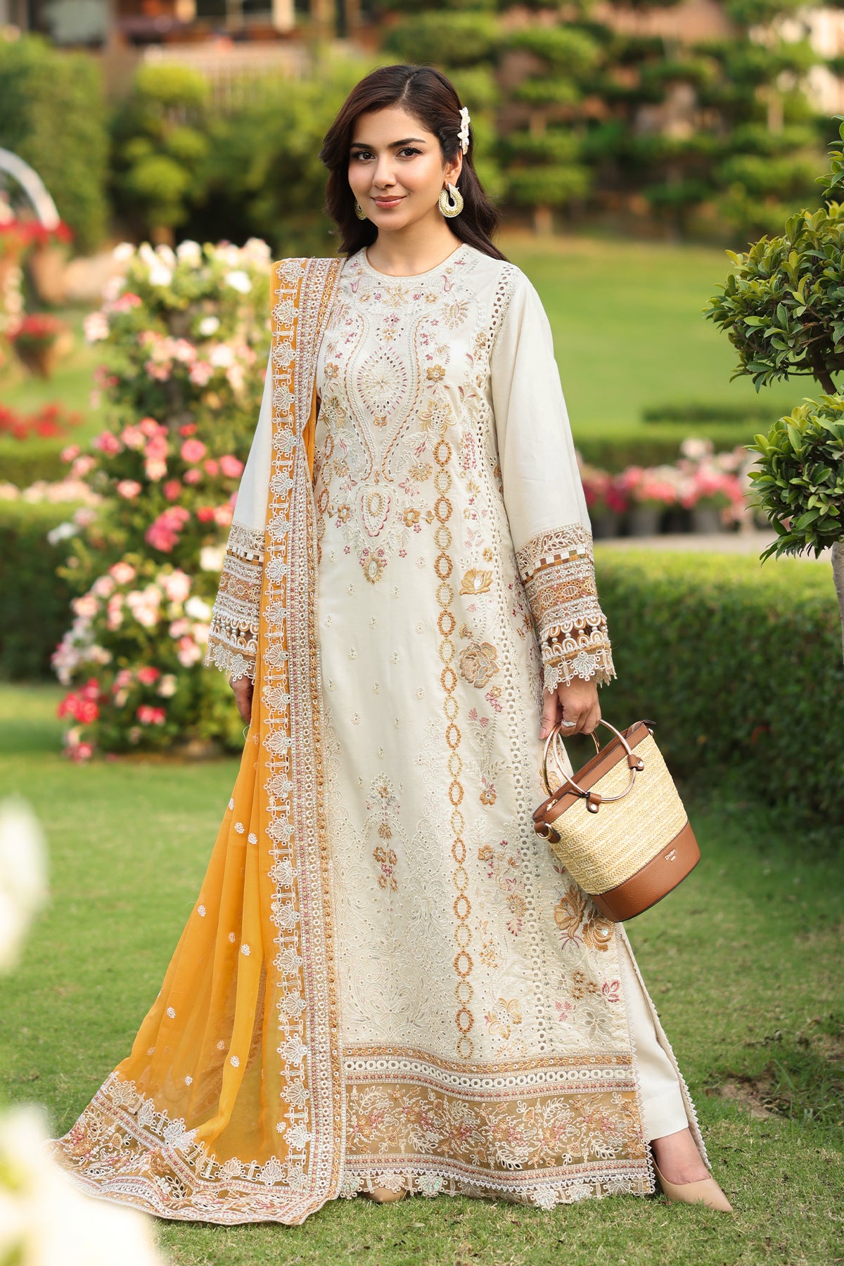 A woman wearing an off-white traditional Lawn dress with embroidery and a dupatta.