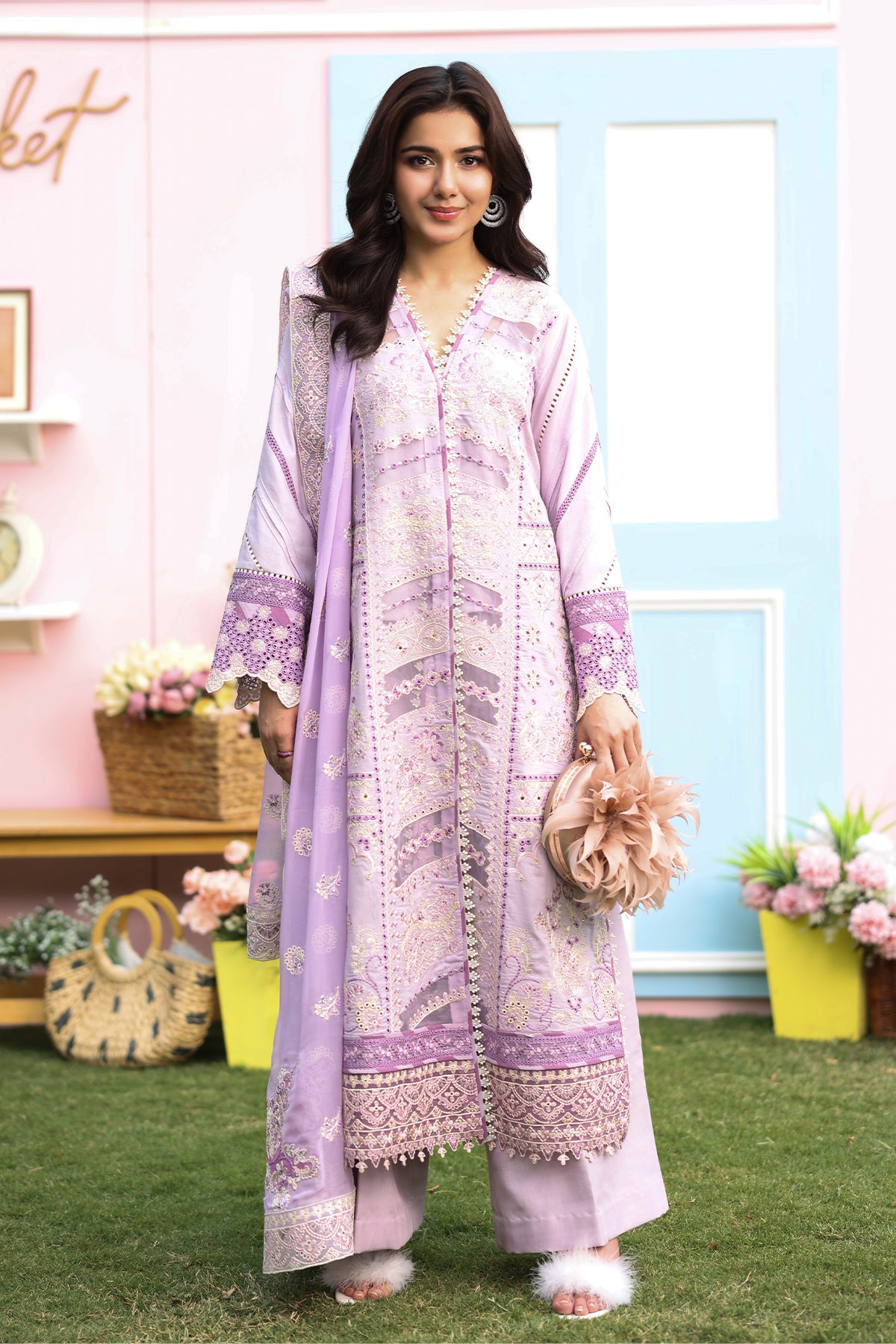 A woman wearing a lilac-colored, embroidered luxury lawn suit with organza borders and a chiffon dupatta.