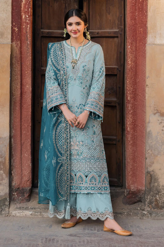 A woman wearing a blue and white embroidered organza three-piece ensemble with a dupatta and trousers.