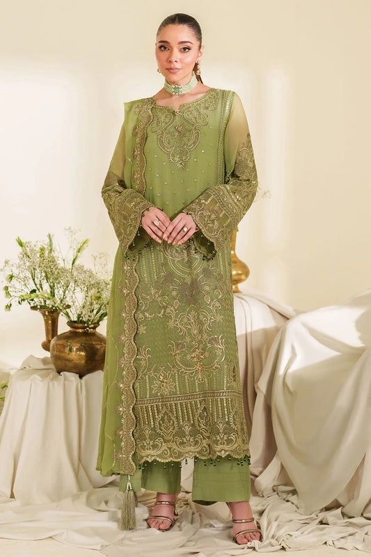 Woman wearing a green embroidered traditional outfit in a decorated room.