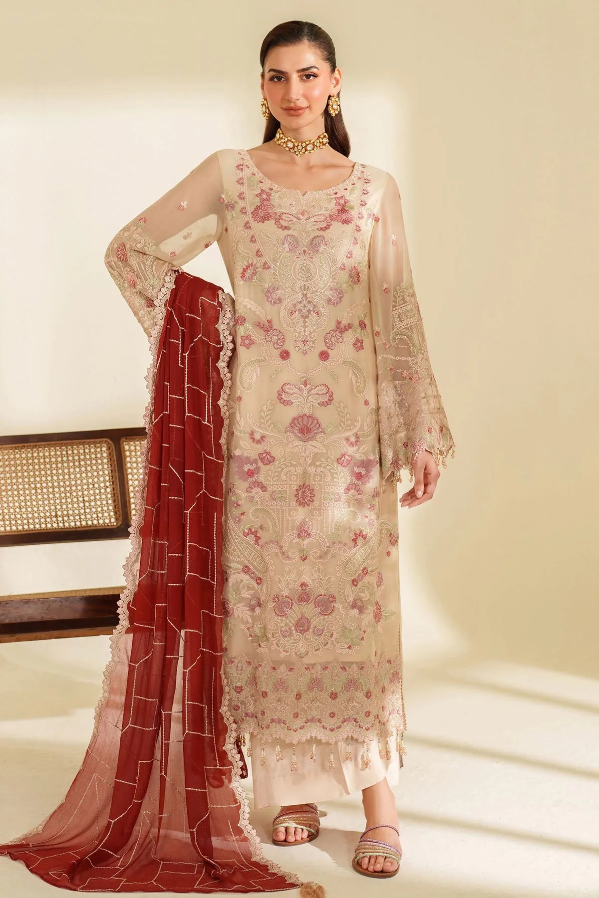 Woman wearing a floral dress with a red dupatta on a neutral background