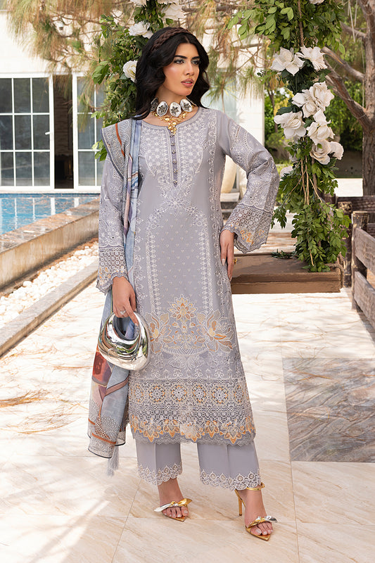 A woman wearing a traditional grey outfit with intricate embroidery, light trousers, and a dupatta with a print. She is standing near a pool with a floral backdrop.