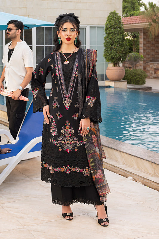 A woman standing by a pool wearing a black traditional outfit with red and white embroidery, including a shirt, dupatta, and trousers.