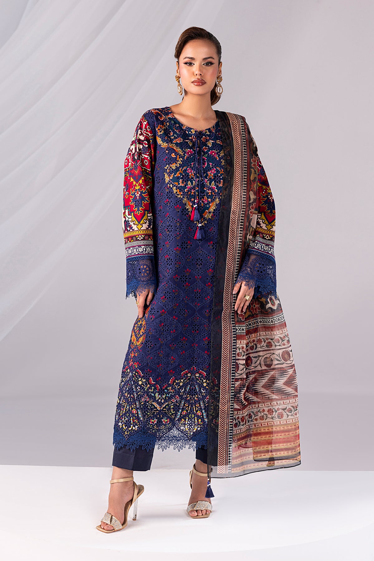 Woman wearing a colorful embroidered dress with a matching dupatta on a white background