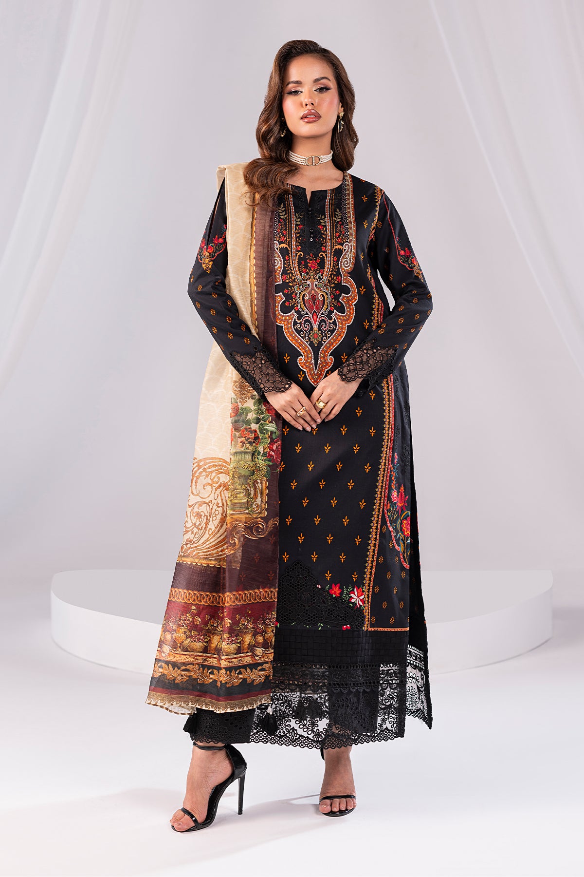 Woman wearing a black embroidered dress with a patterned dupatta on a white background