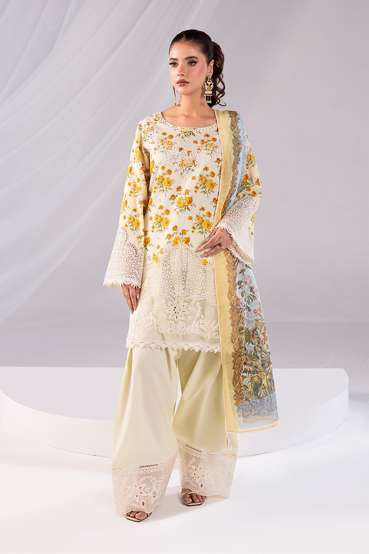 Woman wearing a cream and yellow embroidered traditional outfit on a white background