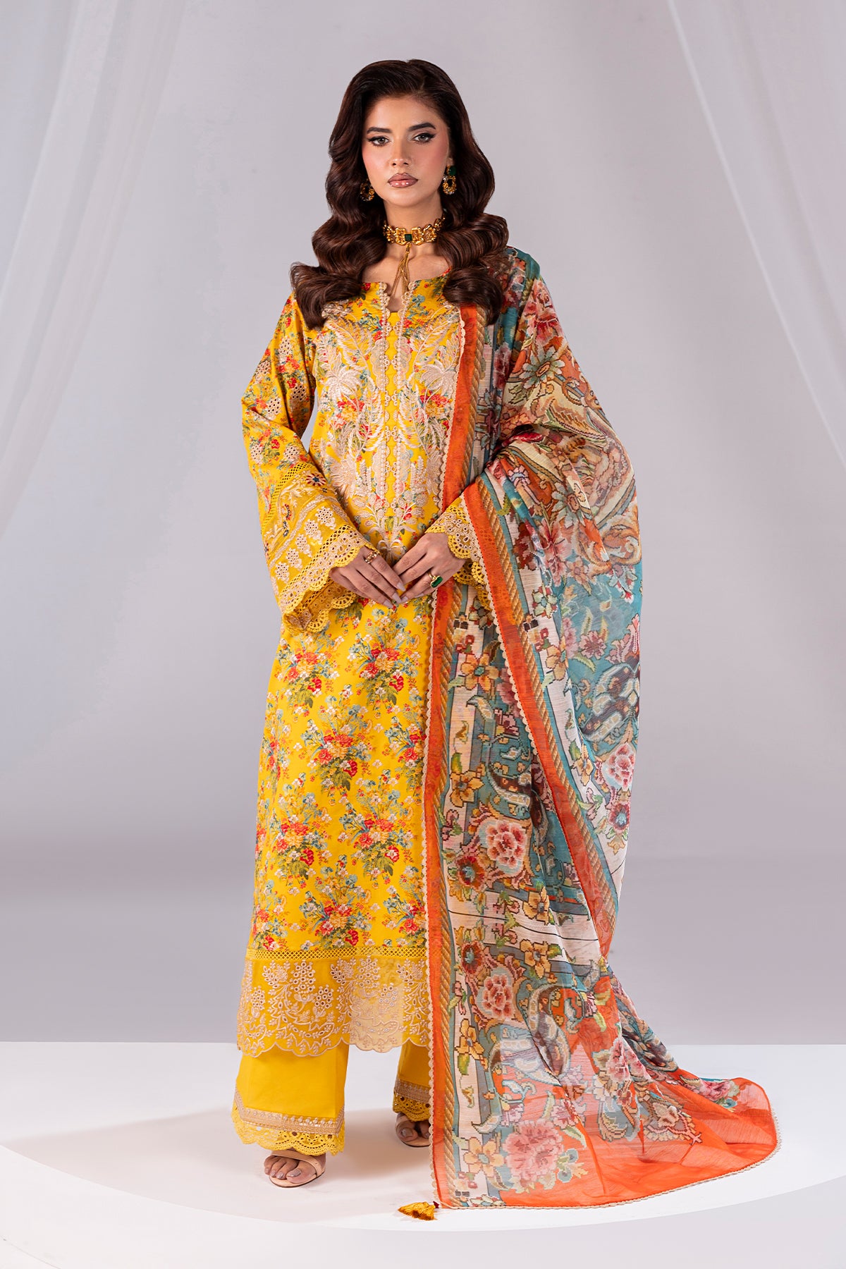 Woman wearing a yellow floral dress with a colorful dupatta on a white background